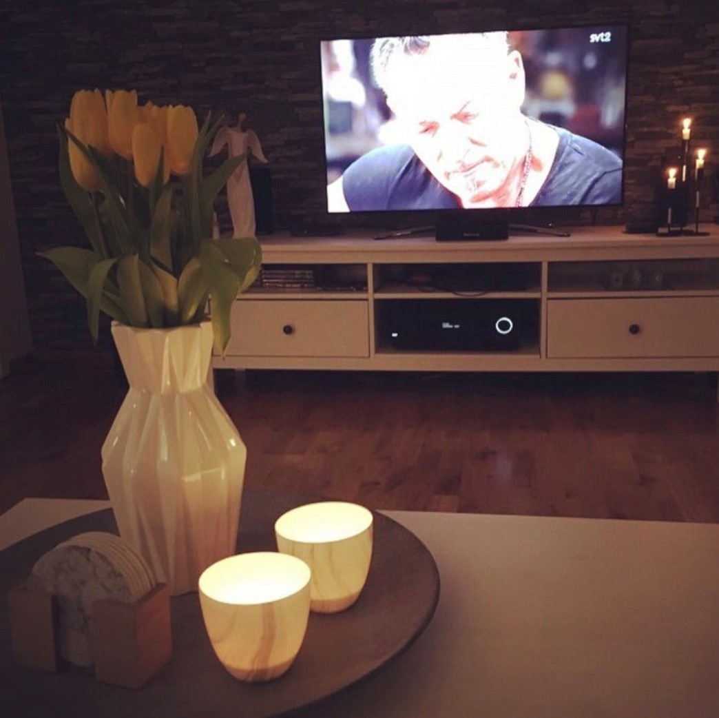 Ljus och blommor på soffbordet framför TVn